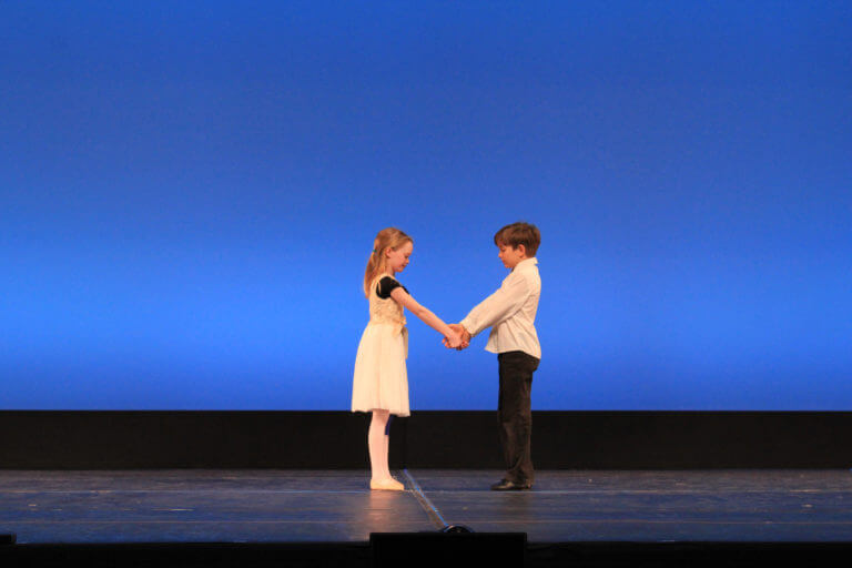 Young girl and boy holding hands on stage